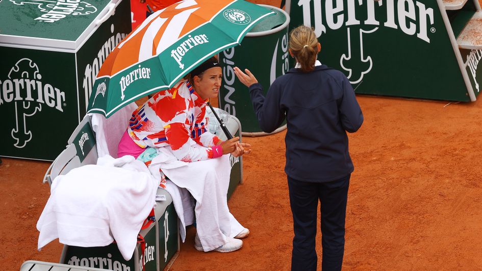 Victoria Azarenka of Belarus speaks with a match official as she shelters under an umbrella